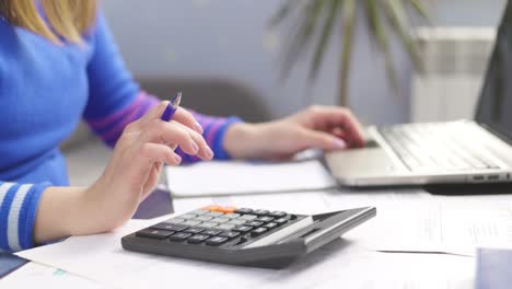mujer usando calculadora para calcular facturas domésticas en el hogar, haciendo papeleo para pagar impuestos