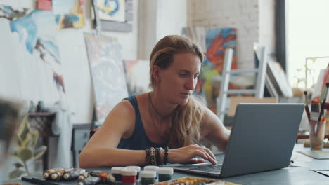 artist working on laptop in art studio