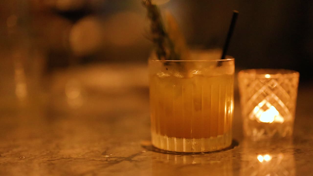 A cocktail is artfully garnished in a dimly lit bar setting, creating a warm and inviting atmosphere