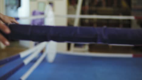 A-female-boxer-entering-the-boxing-ring-coming-to-the-corner-and-resting-with-her-arms-on-the-ring-ropes.-Slow-Motion-shot