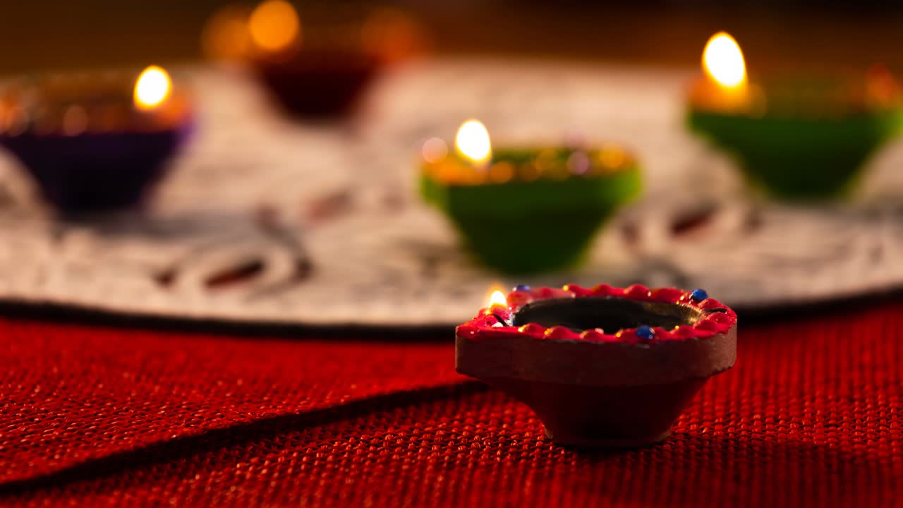video de velas de diwali encendidas en una superficie con patrones rojos y blancos