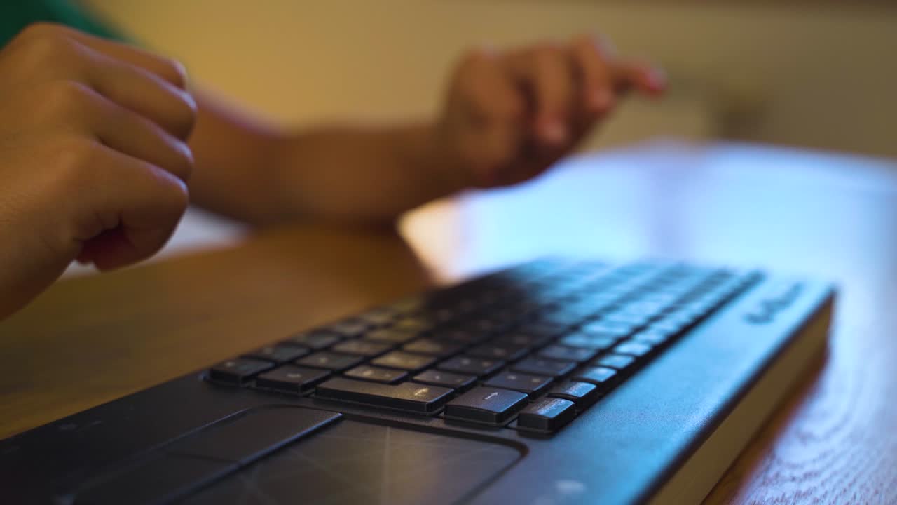 Close-up of a child's hands typing on a keyboard