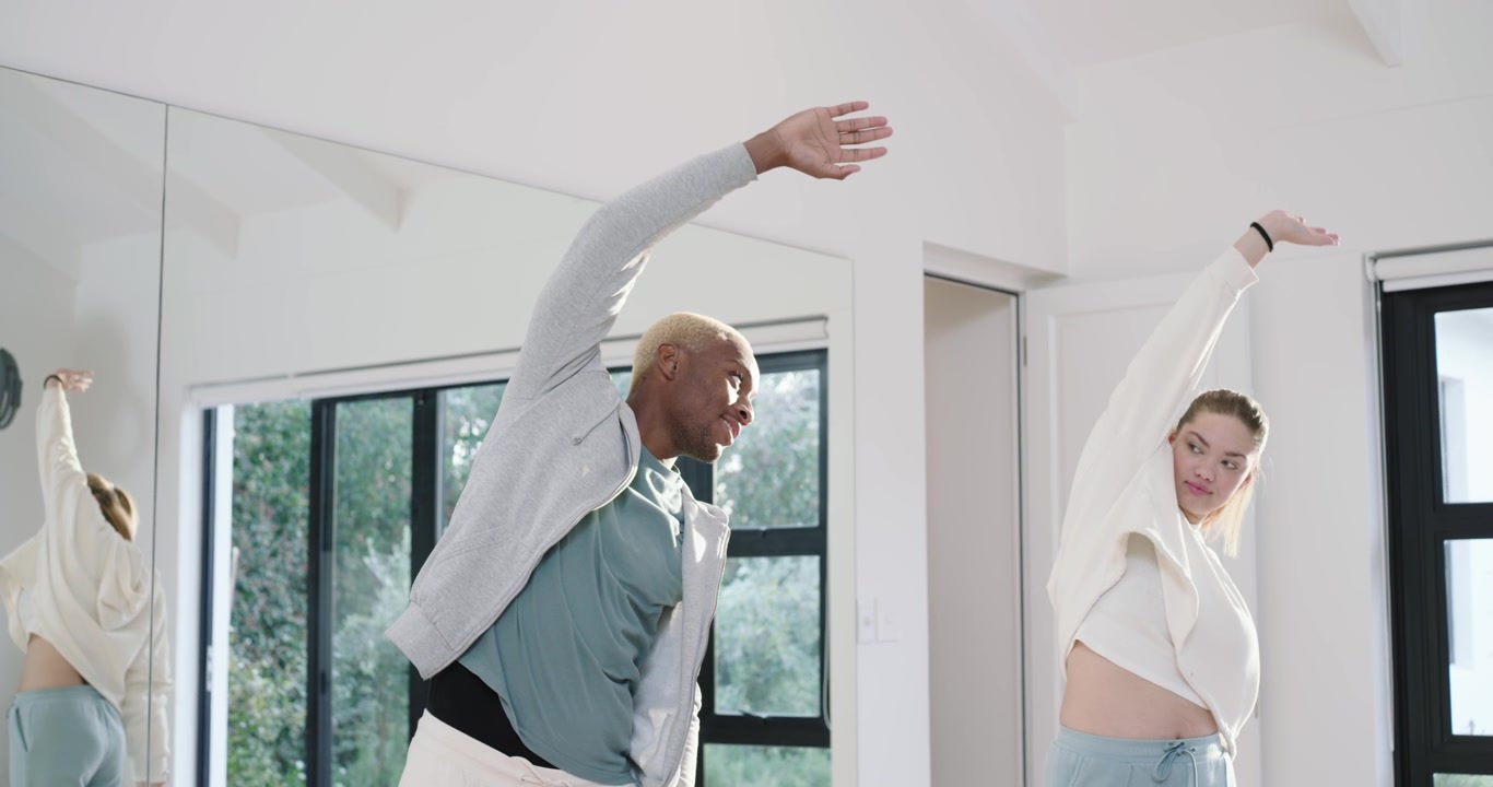 Diverse Freunde beginnen mit Arm-Aufwärmübungen, spiegeln Dehnübungen im Spiegel, während sie sich auf das Training vorbereiten.