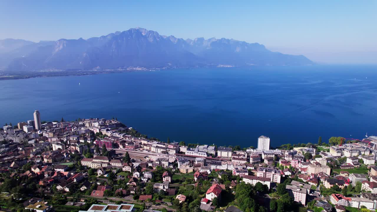 High mountains of French Alps in the background of Montreux cityscape at Lake Geneva in Switzerland seen from above on a sunny hazy day and below the a9 freeway in the foreground