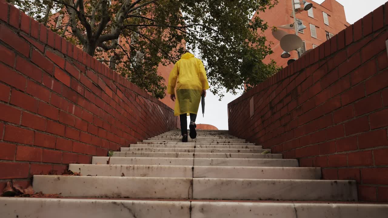 Business man tourist person with umbrella and raincoat on rainy european city street, lights reflecting, walking in Barcelona or Amsterdam during the rain