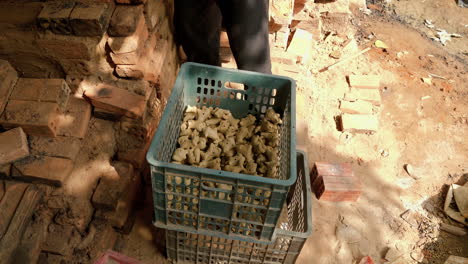 a man taking animal-shaped clay flutes out of a plastic box, showcasing thanh ha's unique ceramic craft