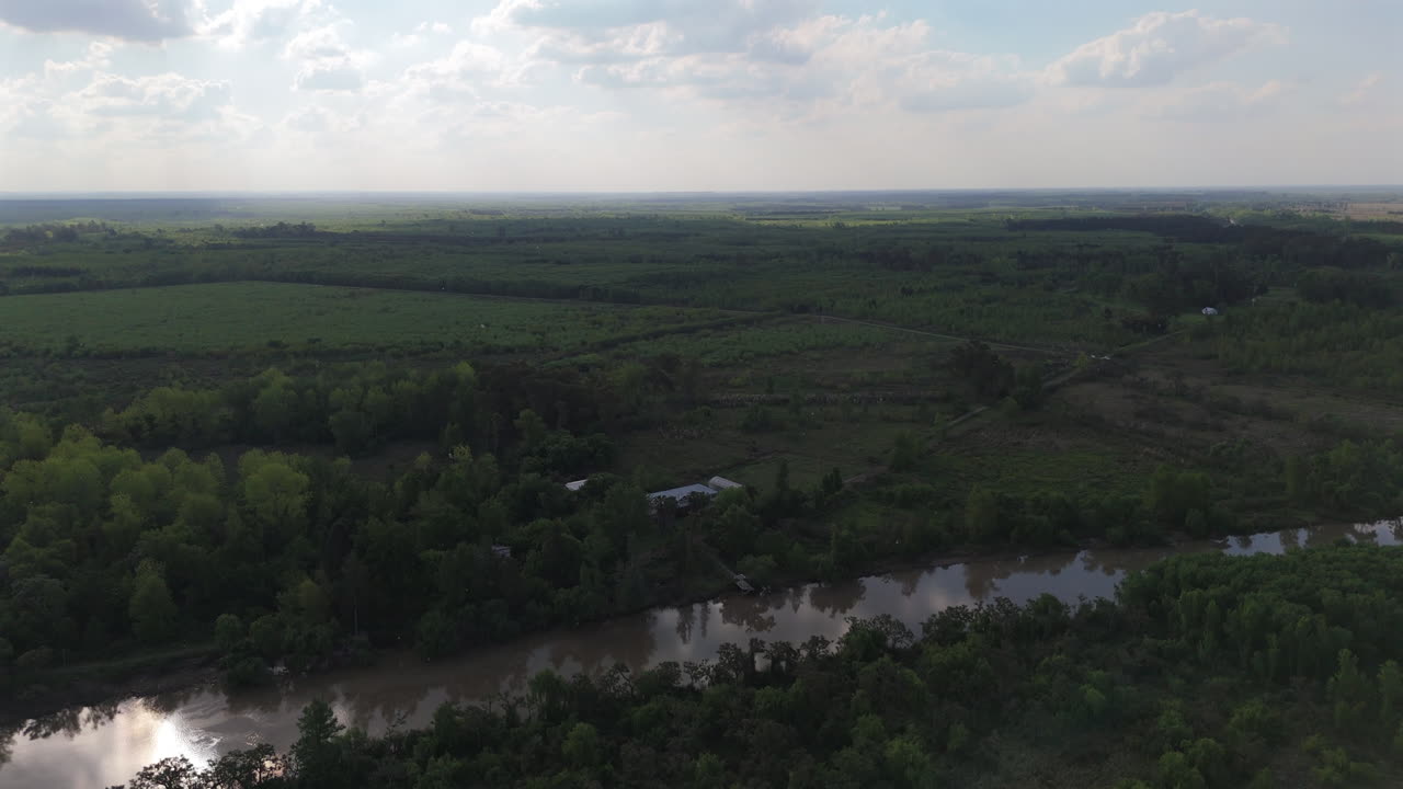 Drone footage showing isolated rural buildings near a calm river surrounded by vegetation in the Argentine Delta