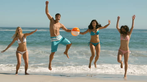 amigos felices saltando y jugando en la playa