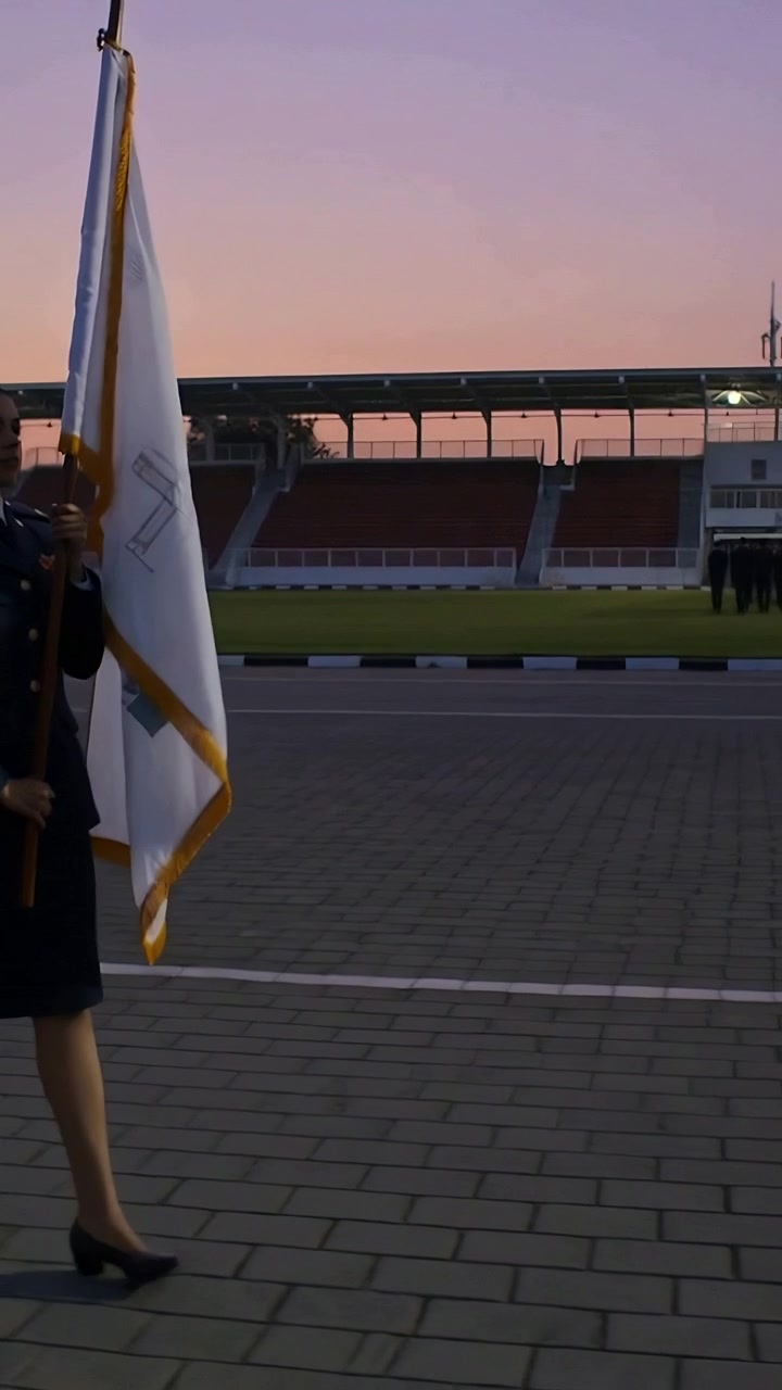 Video vertical: Abanderado uniformado marchando, sosteniendo una bandera blanca en un estadio a la señal, con espacio para texto.
