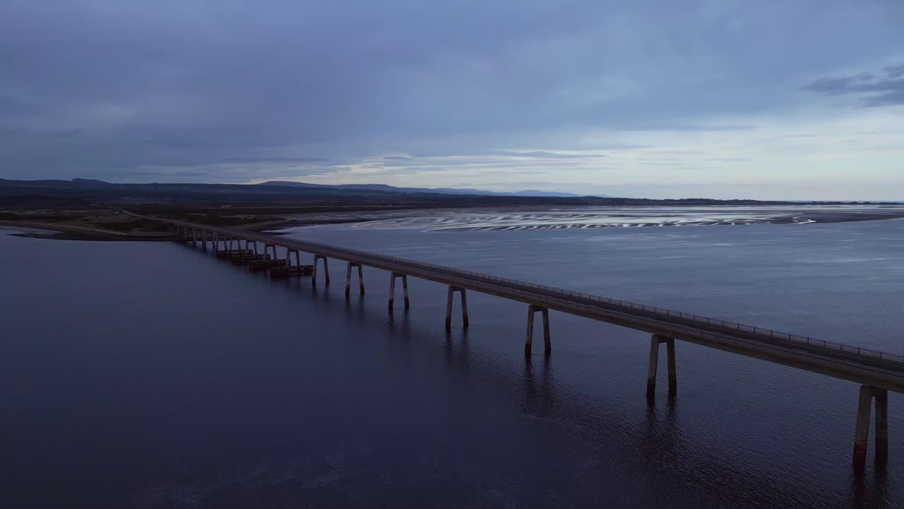 panorámica del puente sobre el océano en escocia para revelar el paisaje de la puesta de sol detrás de él
