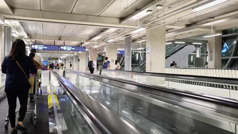 people using moving walkway at bangkok airport