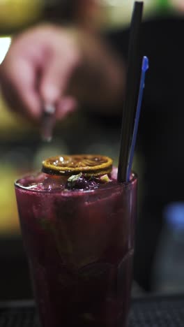 delicious closeup macro vertical shot of crafted tropical berry drink at hotel bar, diced lime decor on top