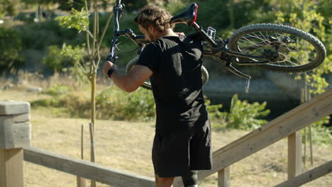 Hombre-Enfocado-Con-Discapacidad-Levantando-Bicicleta-Y-Bajando-Escaleras