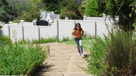 Caucasian-girl-wearing-face-mask-with-backpack-standing-in-the-garden-at-home