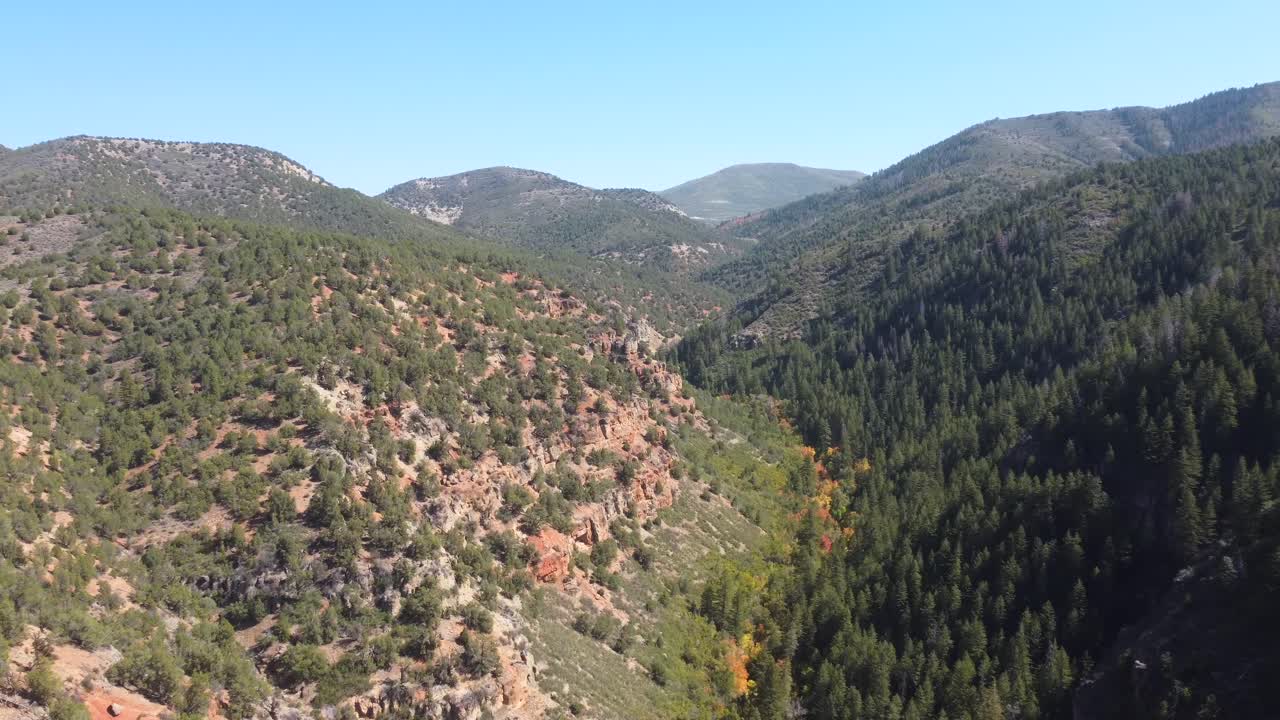 Aerial view of a rugged Utah canyon and hiking trail winding toward natural hot springs. Perfect for travel and outdoor storytelling