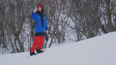 slow motion shot of a snowboarder using a smartphone while driving on a ski slope