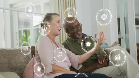 icons representing education and technology animation over couple using tablet on couch