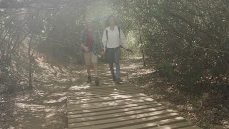 Happy-african-american-couple-hiking-on-boardwalk-in-forest,-slow-motion