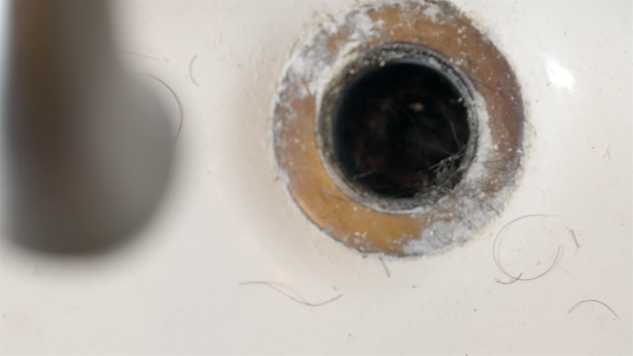 Top down views of a disgusting blocked drain hole with hair and grime
