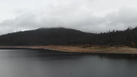 Aerial-shot-of-dark-storm-clouds-rolling-in-over-a-mountain-lake