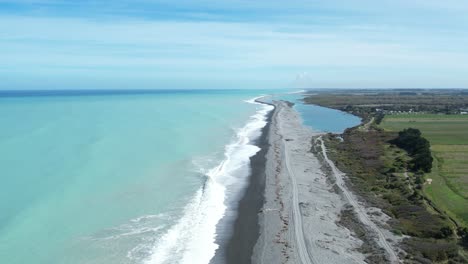 Aerial-climb-showing-beautiful-turquoise-color-of-South-Pacific-Ocean,-farmland-and-Rakaia-Lagoon