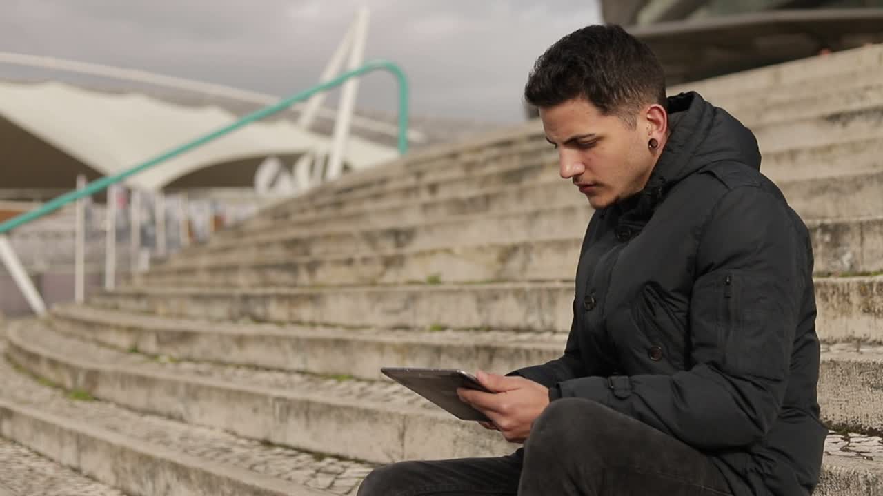 Concentrated young freelancer working with tablet outdoor
