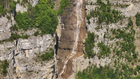 seerenbach falls spills from rugged alpine cliffs into a deep green valley, framed by dense forests and dramatic rocky terrain in the swiss landscape