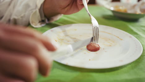 hungry depressed chef man divides a sausage on his plate for his meager dinner