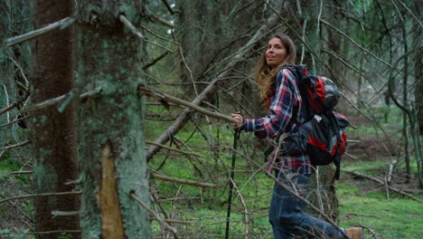 smiling hiker walking between trees in forest