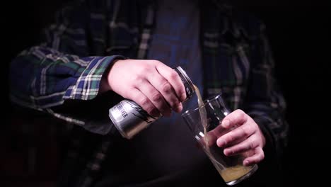verter la lata de cerveza en un vaso a cámara superlenta en un estudio negro