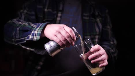 pouring beer can into glass super slow motion in black studio