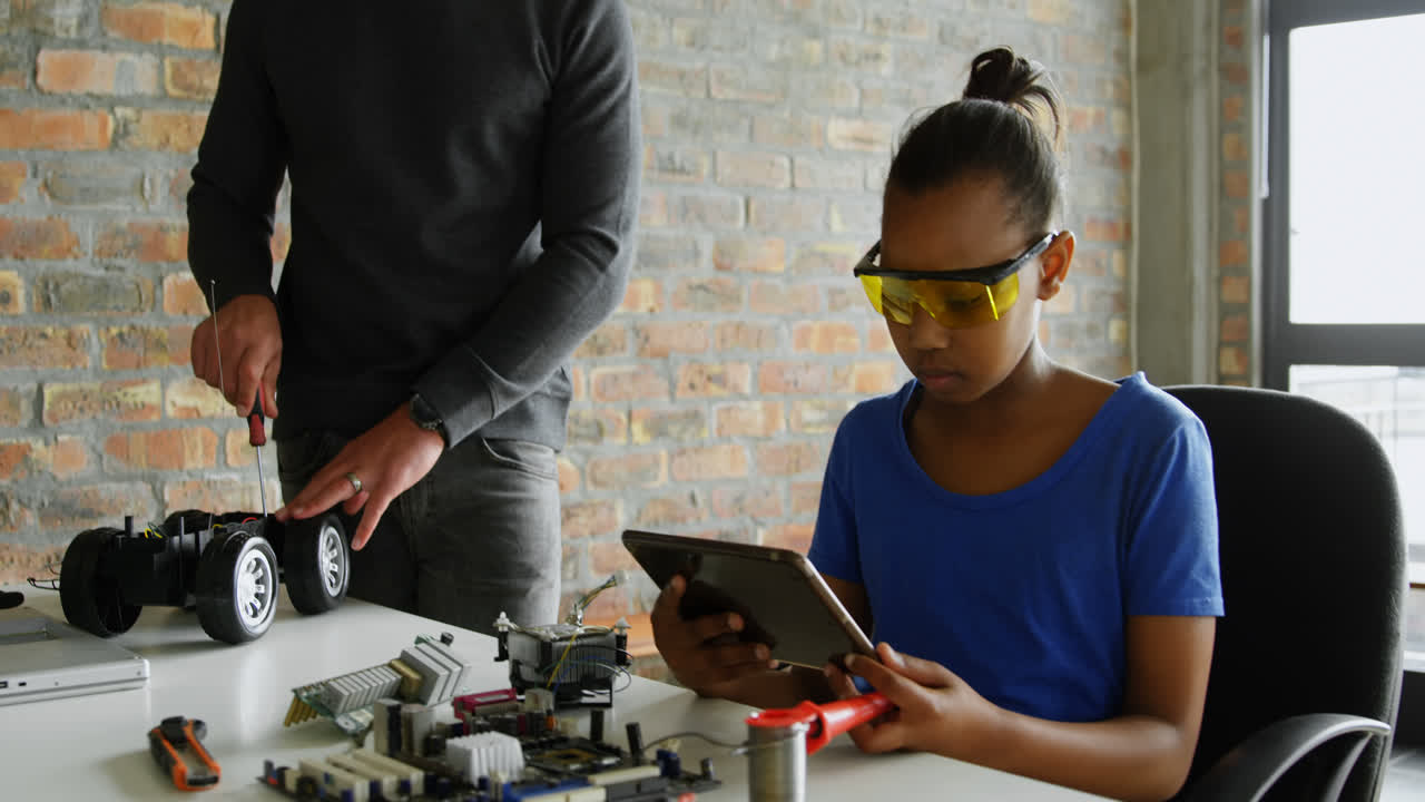 hija usando una tableta digital mientras el padre repara un coche eléctrico 4k