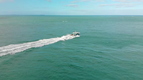 barco en el océano azul con la isla stewart en el fondo en un día soleado y nublado - bluff, nueva zelanda - drone aéreo