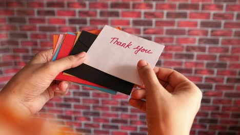 person holding a thank you note and colorful envelopes