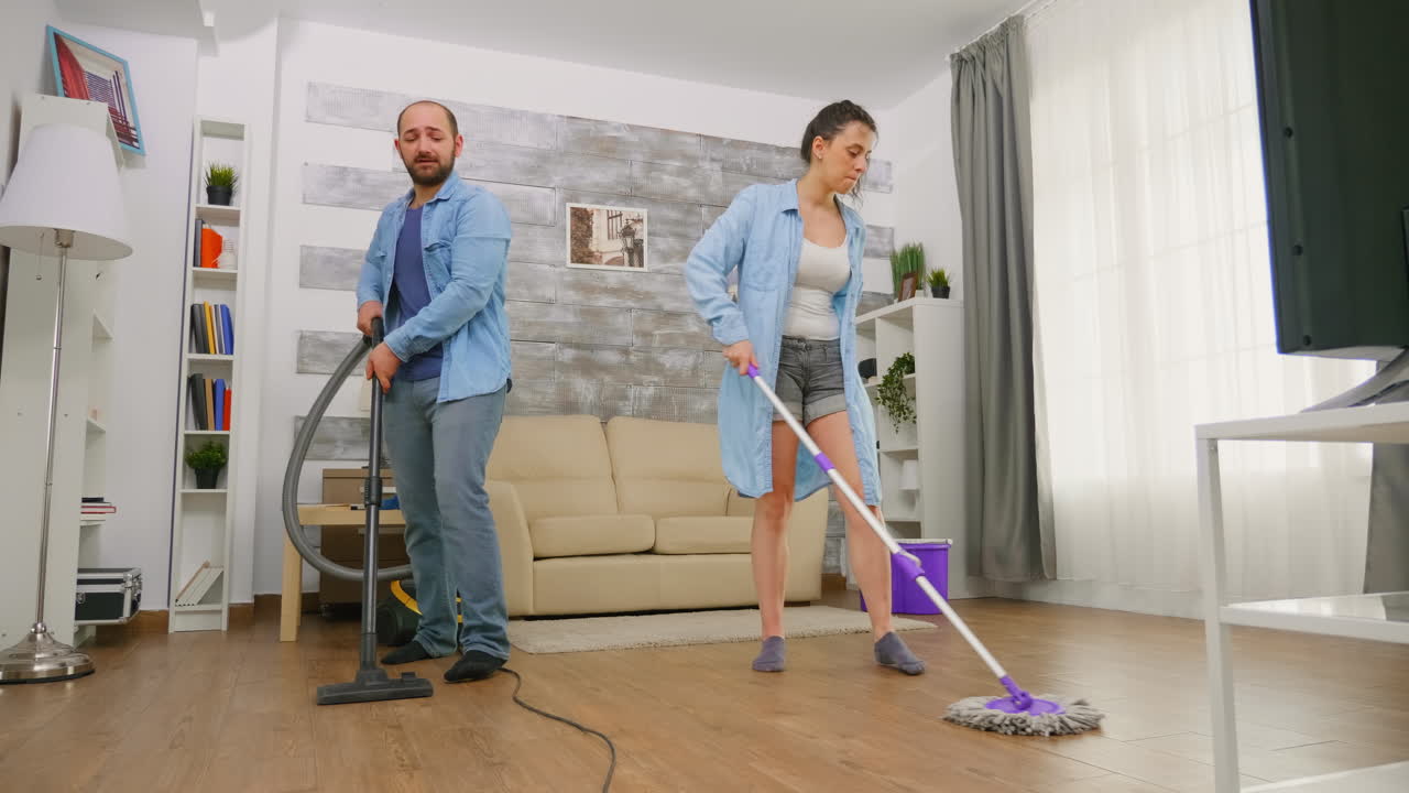 pareja ayudándose mutuamente a limpiar la habitación