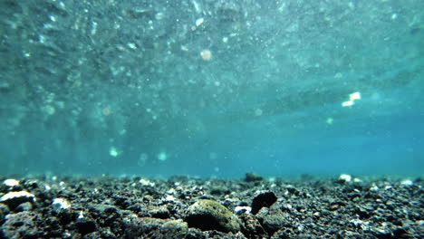 underwater shot of blue glittering water and stony sea bed in hawaii