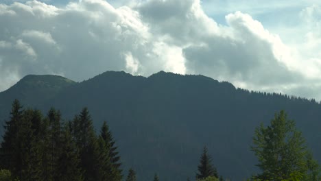 Lapso-De-Tiempo-De-Nubes-En-Movimiento-Rápido-Sobre-Montañas-Oscuras-Y-Altas-Con-árboles-En-Primer-Plano