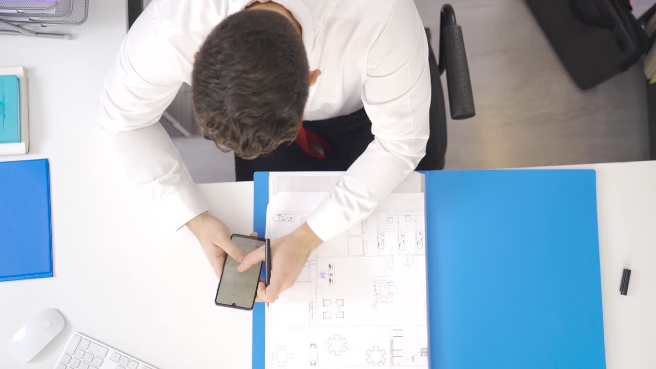 el arquitecto está trabajando en el proyecto que ha dibujado en su oficina.