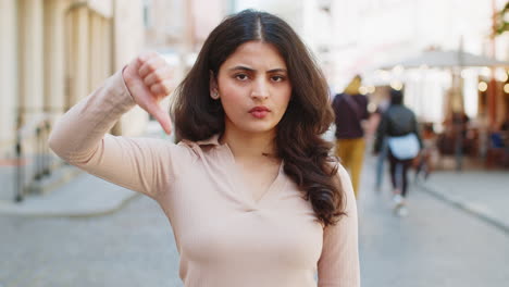 Upset-Indian-woman-showing-thumbs-down-sign,-disapproval,-dissatisfied-bad-work,-mistake-in-city