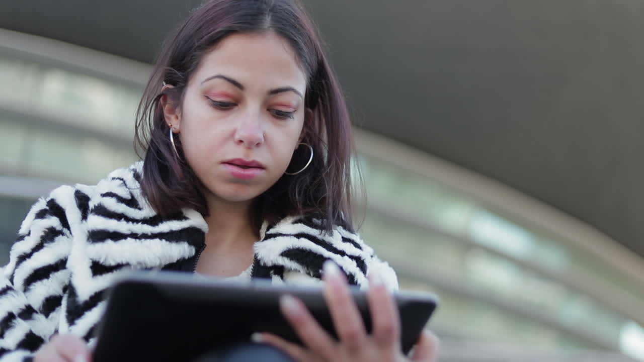 mujer joven pensativa mirando la tableta al aire libre