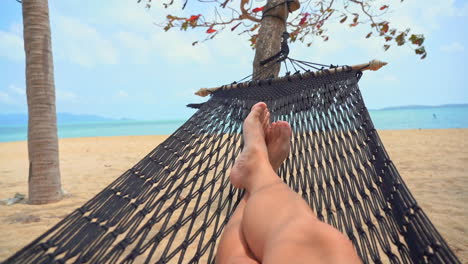 Bare-Legs-in-Hammock-on-Sandy-Beach-on-Tropical-Island,-Light-Breeze