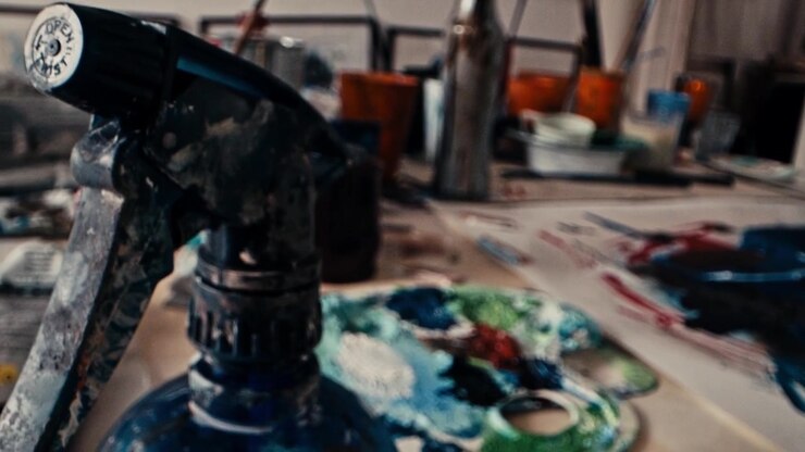 Low angle slider move over a paint palette with thick colors to a spray bottle