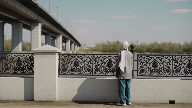 Donna musulmana con lungo hijab si trova vicino alla recinzione sul lungomare.