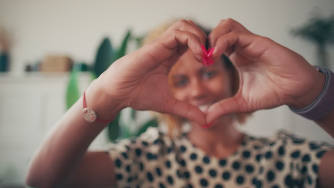 Young african american woman millennial shows valentine heart made of fingers