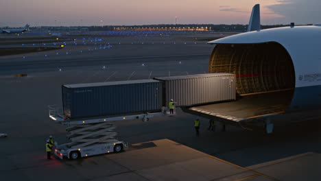 cargo plane being loaded with shipping containers at dusk