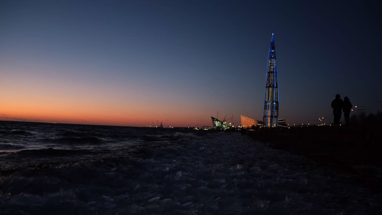 Sunset at the beach with a tall illuminated tower
