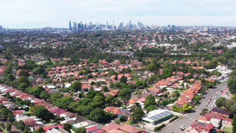 Disparo-Aéreo-De-Un-Dron-Volando-Hacia-Atrás-Sobre-El-Suburbio-Interior-occidental-De-Haberfield-Con-El-Horizonte-De-La-Ciudad-En-La-Distancia-En-Sydney,-Australia