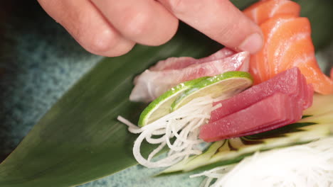 sushi chef arranging the fresh salmon fillet and tuna with lime, cucumber, and shredded radish