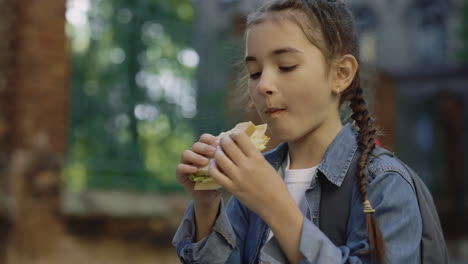 young girl eating a sandwich