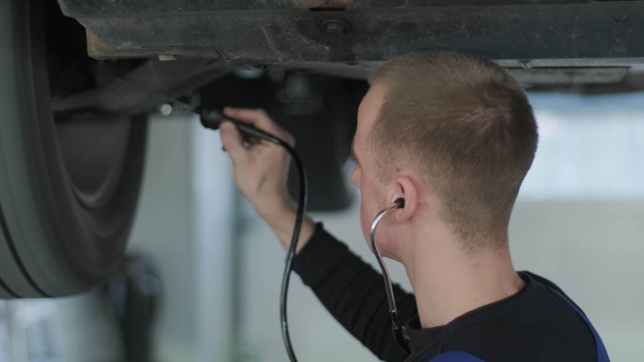 mecánico inspeccionando el tren de aterrizaje del automóvil en el pozo de servicio